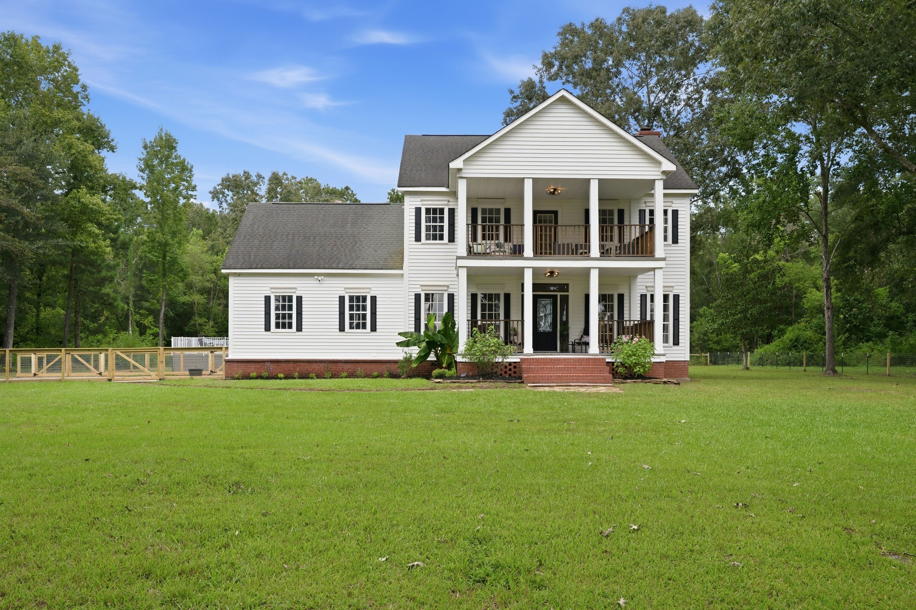 A two-story house with a front porch and a fenced yard.