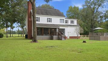 A two-story house with a large front porch, a brick chimney, and a fenced yard.