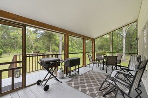 A covered outdoor area with a grill, seating, and a view of the surrounding forest. - Country Living Near Lake Houston - Starry Skies 3 Bedroom Home (Dayton)