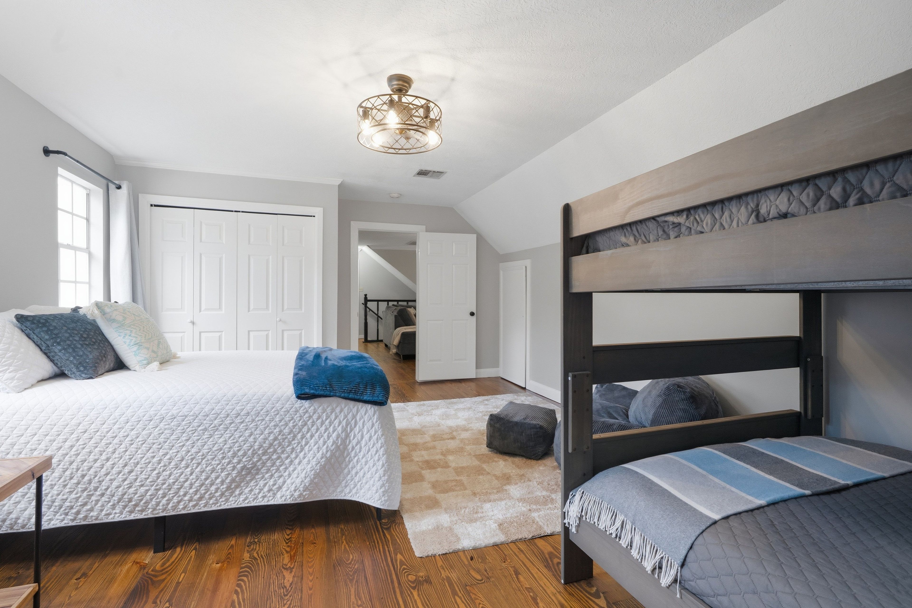 A bedroom with a bunk bed, a queen-sized bed, and a ceiling fan.
