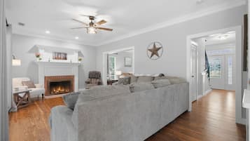 A living room with a fireplace, a sofa, and a ceiling fan.