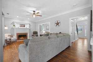 A living room with a fireplace, a sofa, and a ceiling fan. - Country Living Near Lake Houston - Starry Skies 3 Bedroom Home (Dayton)