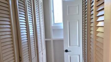 A narrow hallway with a red floor, white doors, and a window at the end.