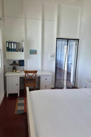 Un dormitorio con cama, escritorio con silla, armario y ventana.