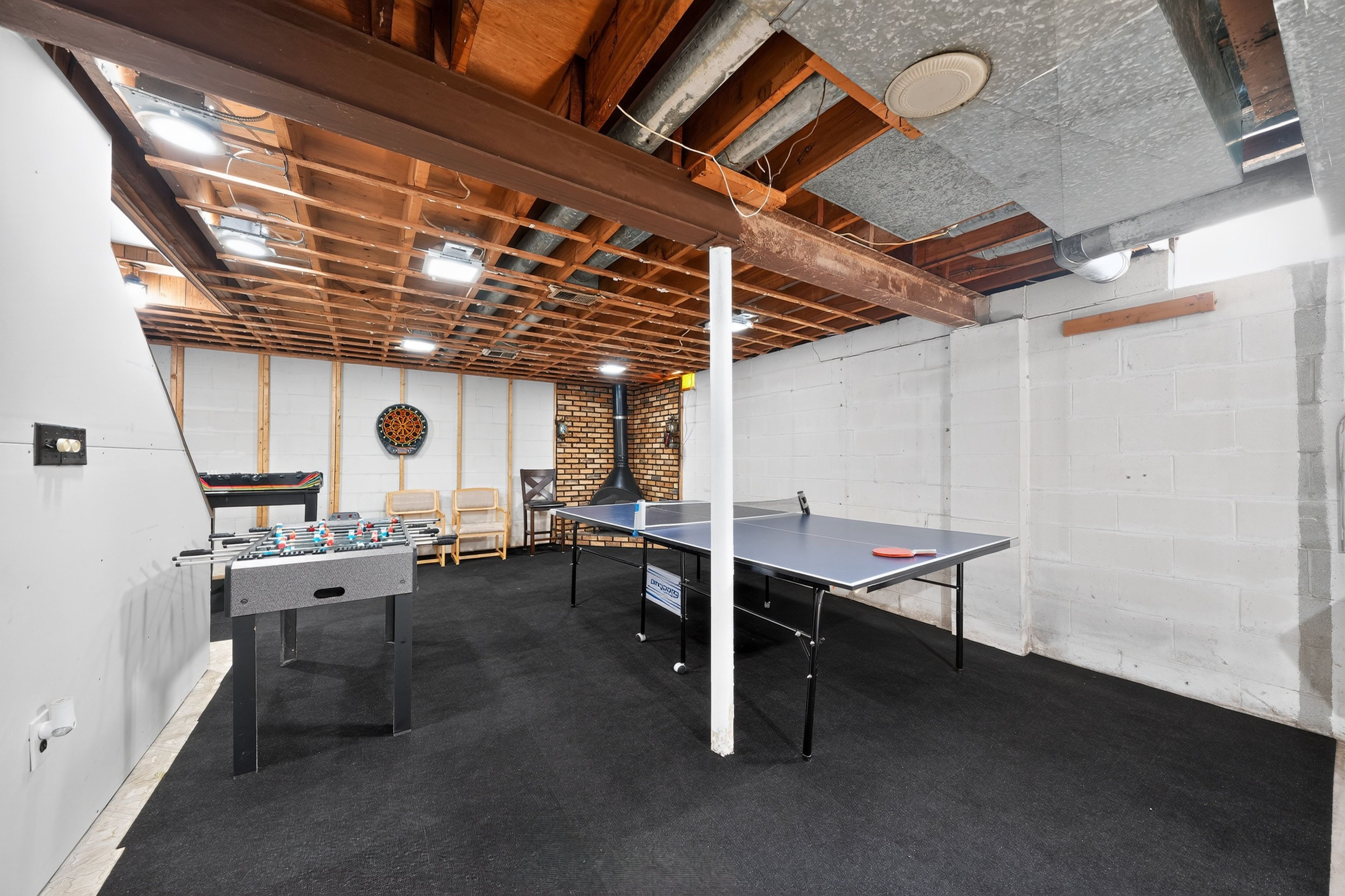 Una habitación con mesa de fútbolín, mesa de ping pong y dardos.
