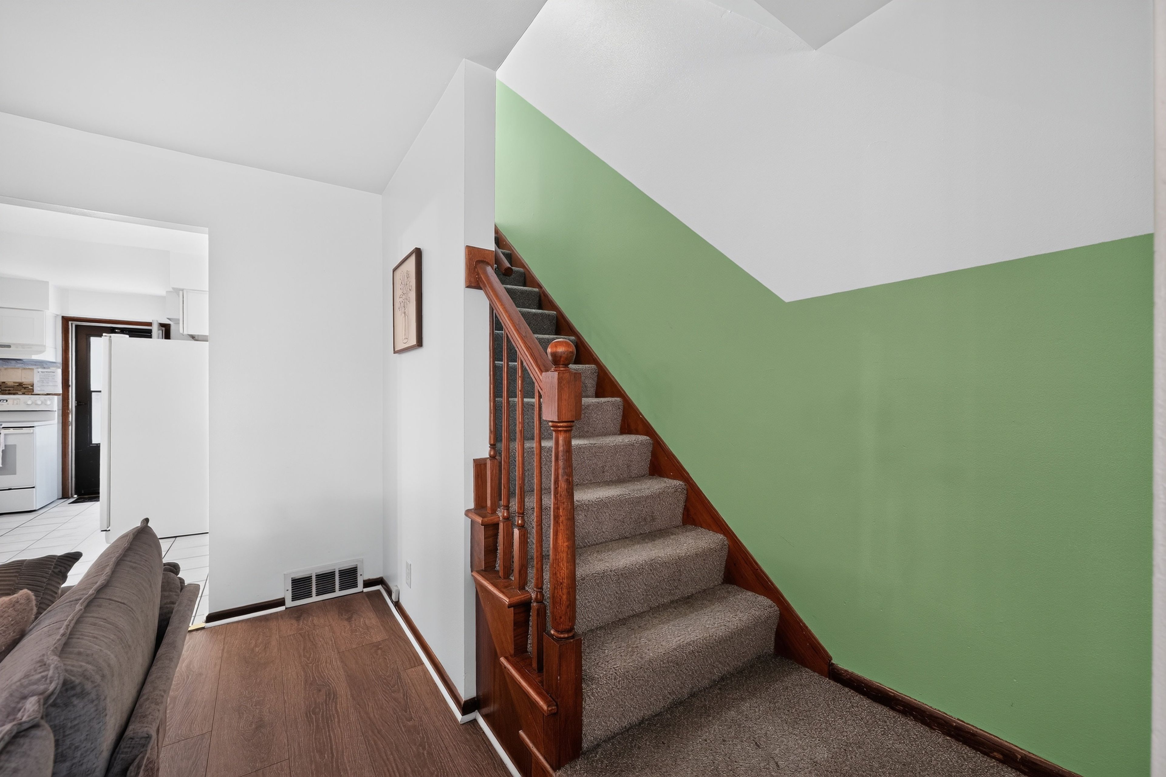 A staircase with wooden handrails and carpeted steps leading to a green wall.