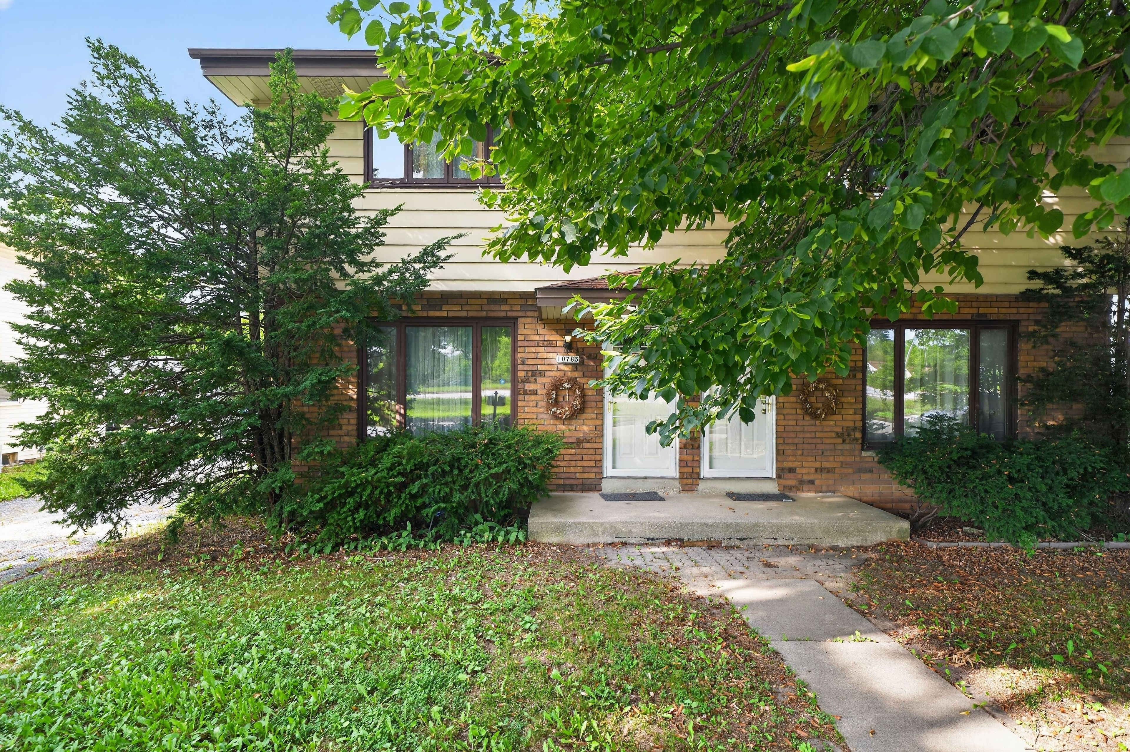 A residential building with a brick facade, large windows, and a front porch.