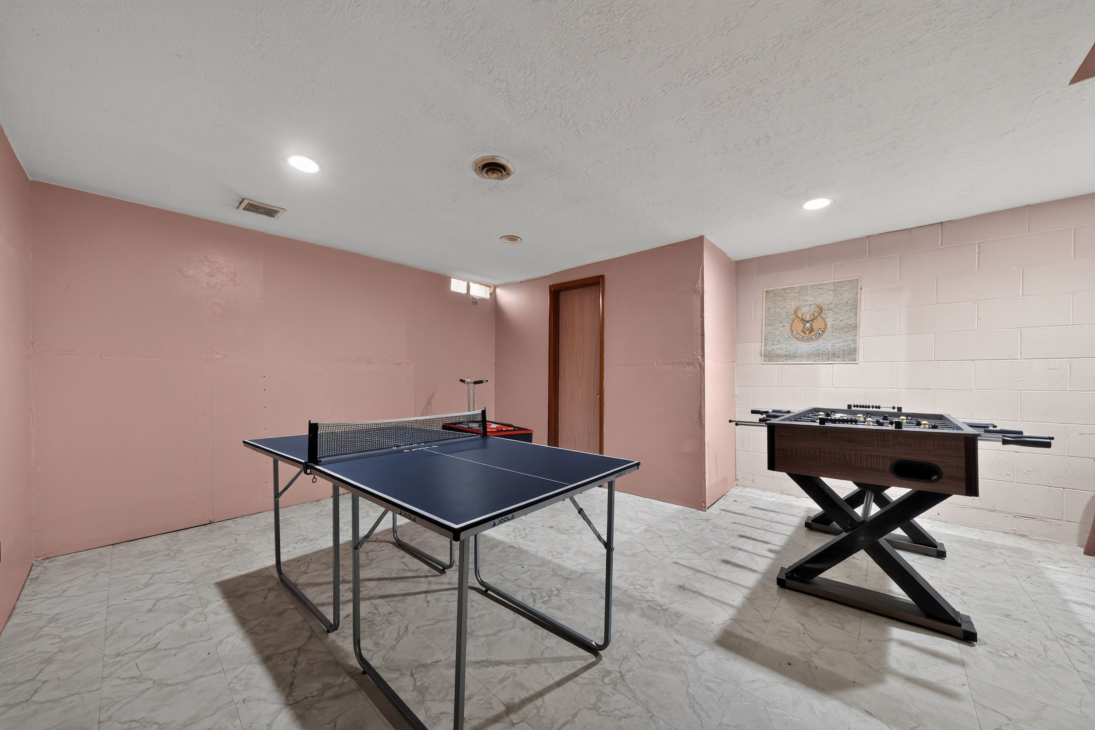 A room with a ping pong table and a foosball table.