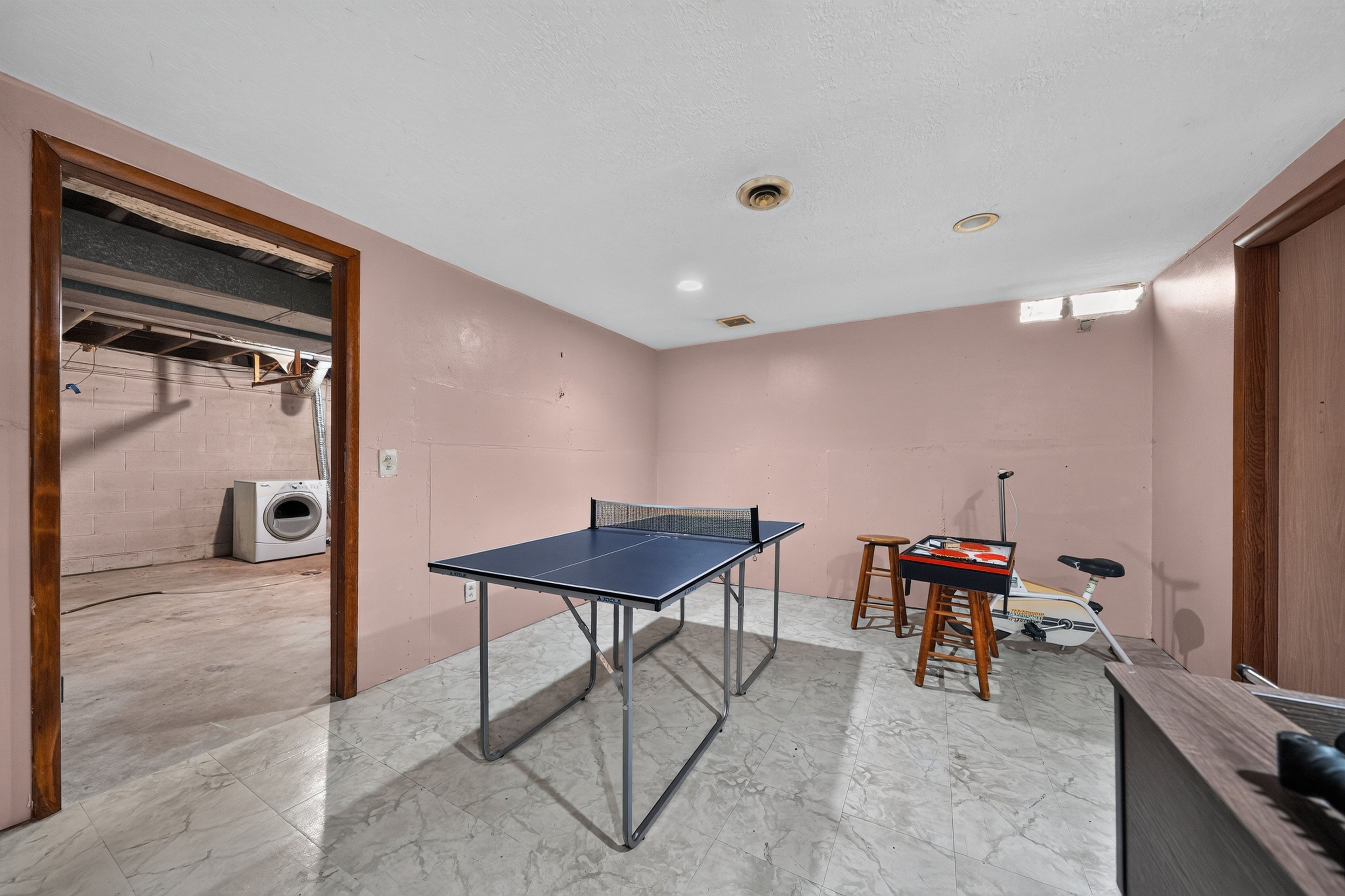 Une pièce équipée d’une table de ping-pong, d’un lave-linge et d’un vélo.