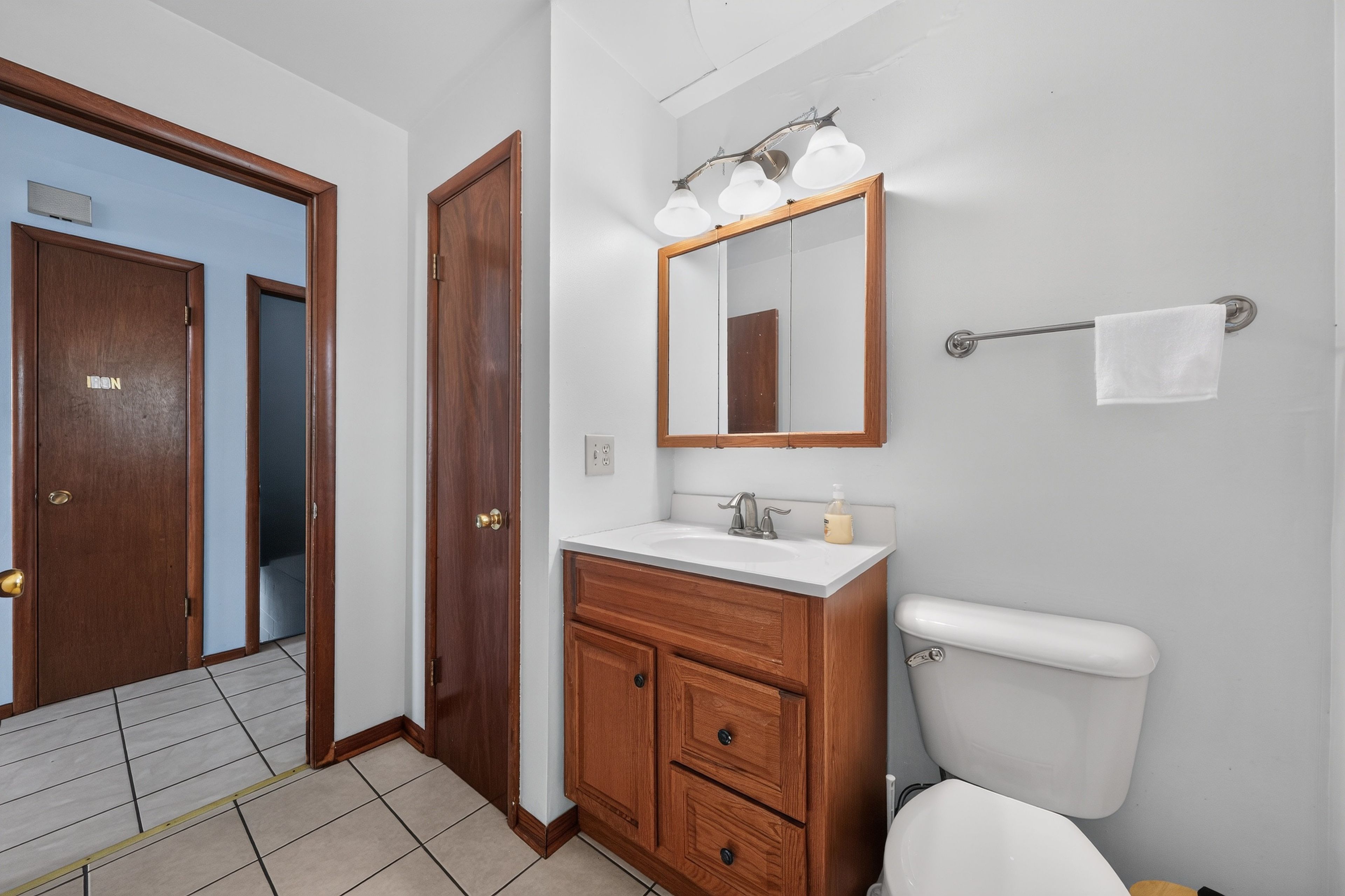 Een badkamer met toilet, wastafel en spiegel.