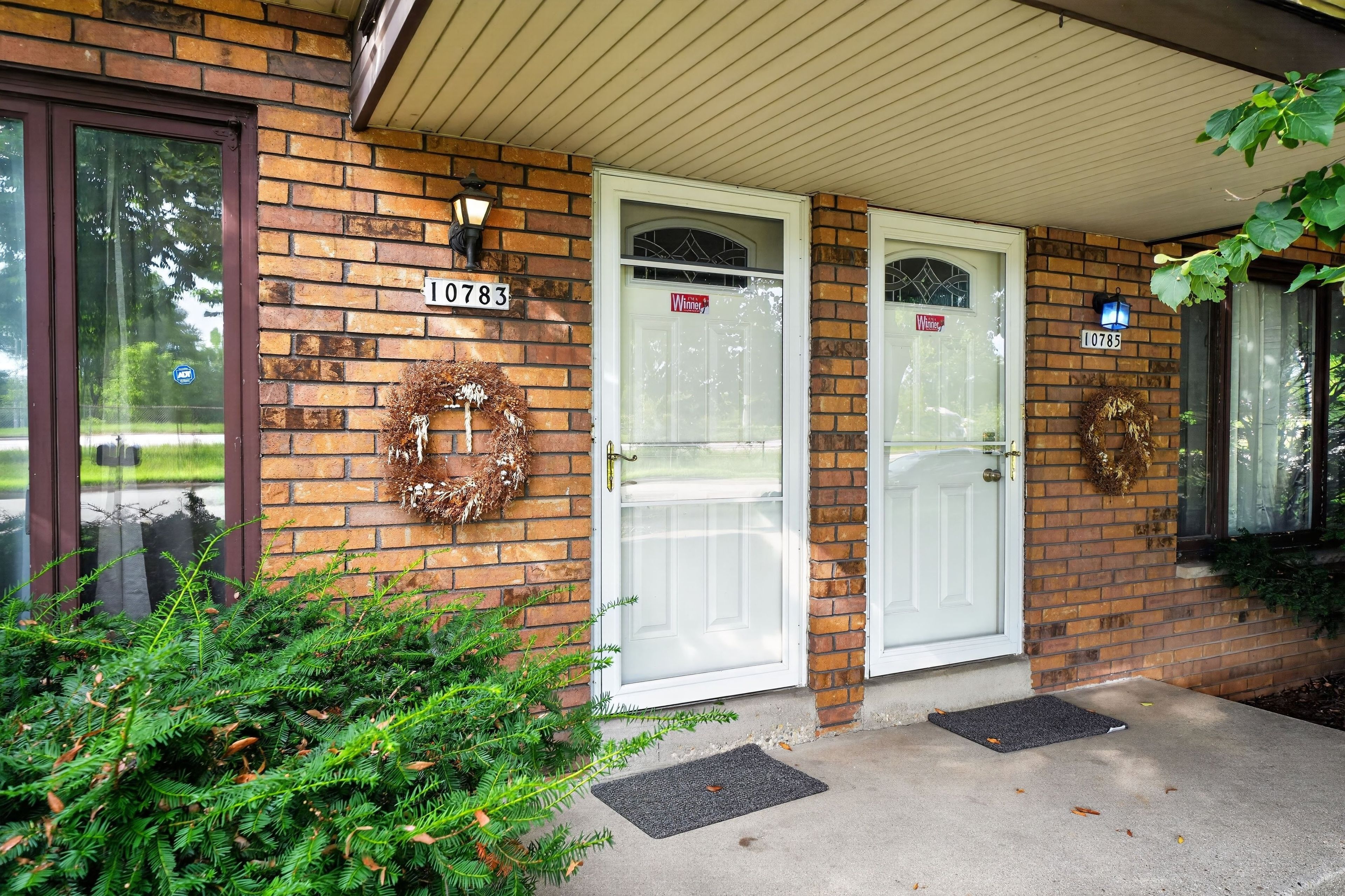 A brick building with two white doors, each with a wreath and a 'Winner' sign.