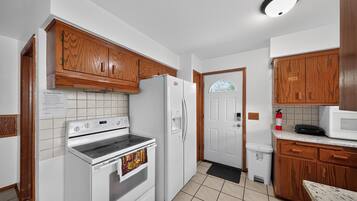 Une cuisine avec des meubles en bois, un réfrigérateur blanc, une cuisinière et un four à micro-ondes.