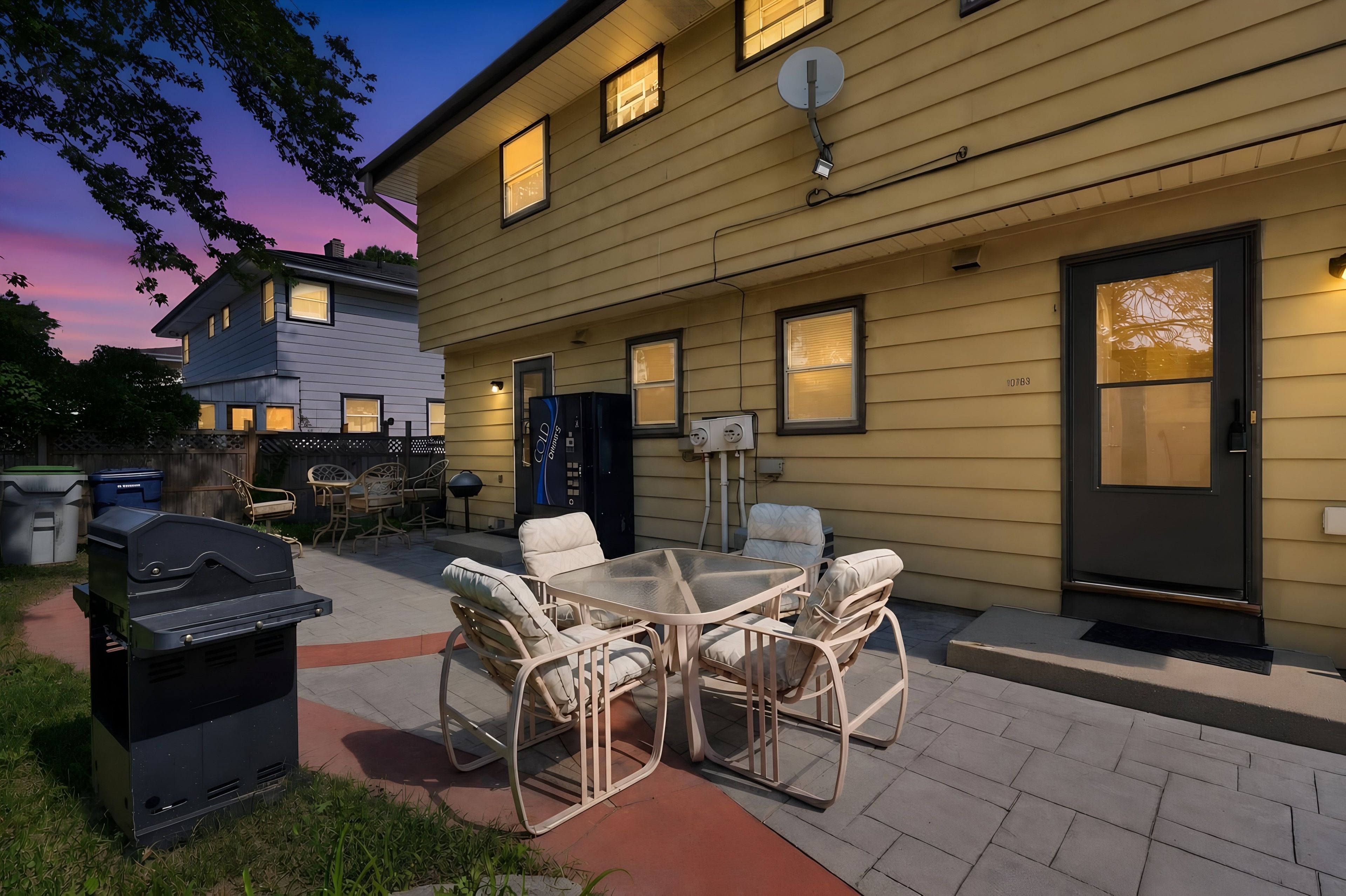 A two-story building with a patio area featuring outdoor furniture and a barbecue grill.