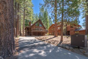 A cabin with a covered porch, a stone pathway, and a large tree in the foreground. - The Landing - Hanson 3 Bedroom Home (Truckee)