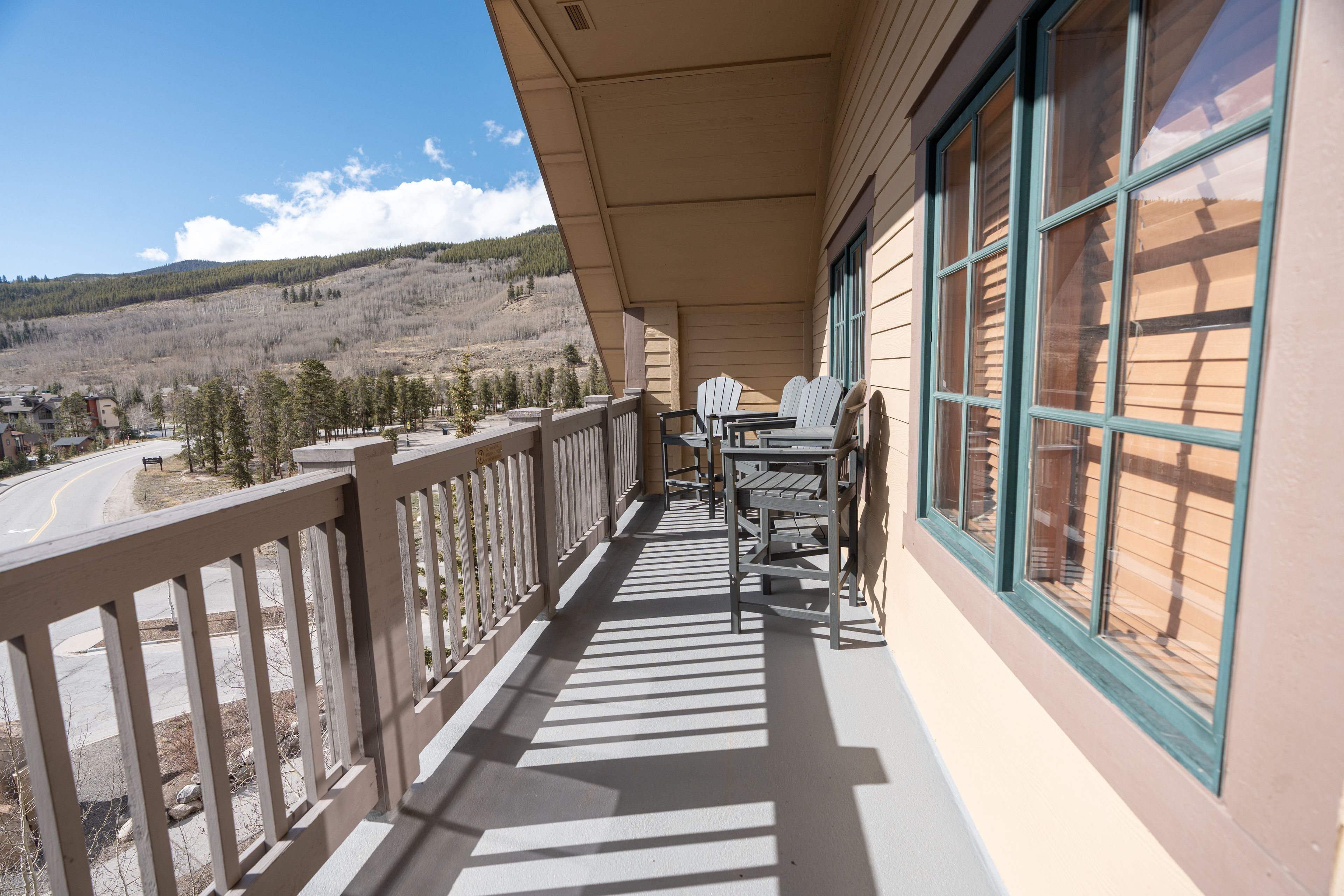 Un balcon donnant sur un paysage montagneux, une table avec des chaises et une balustrade.