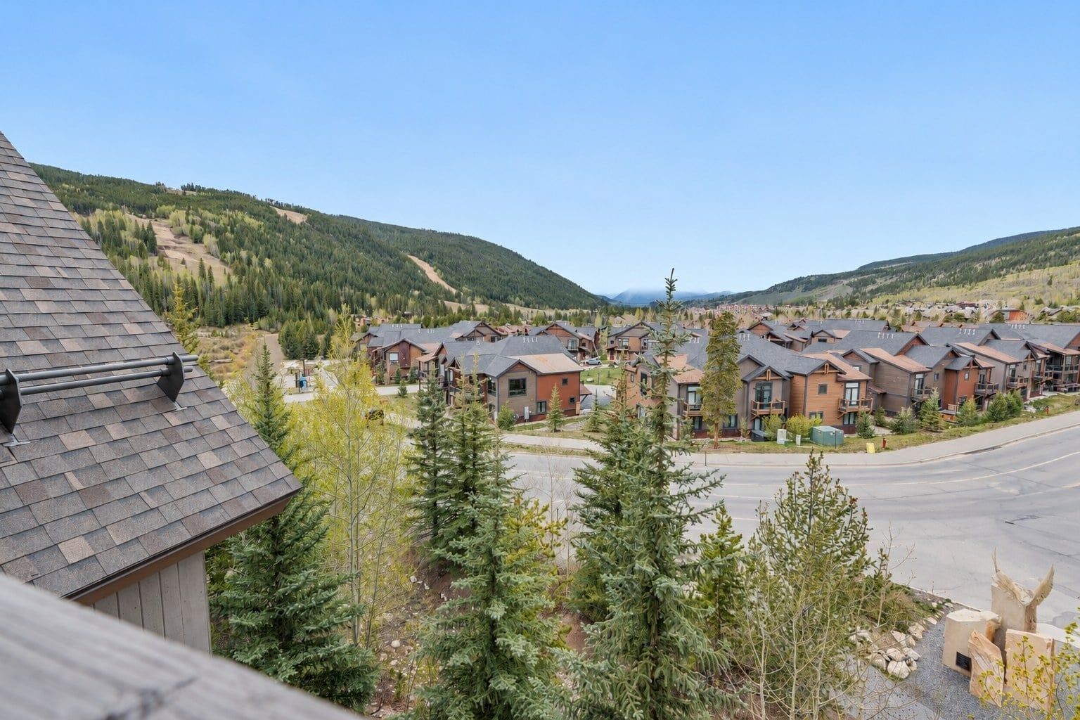 A residential area with multiple houses, a clear sky, and a mountainous backdrop.