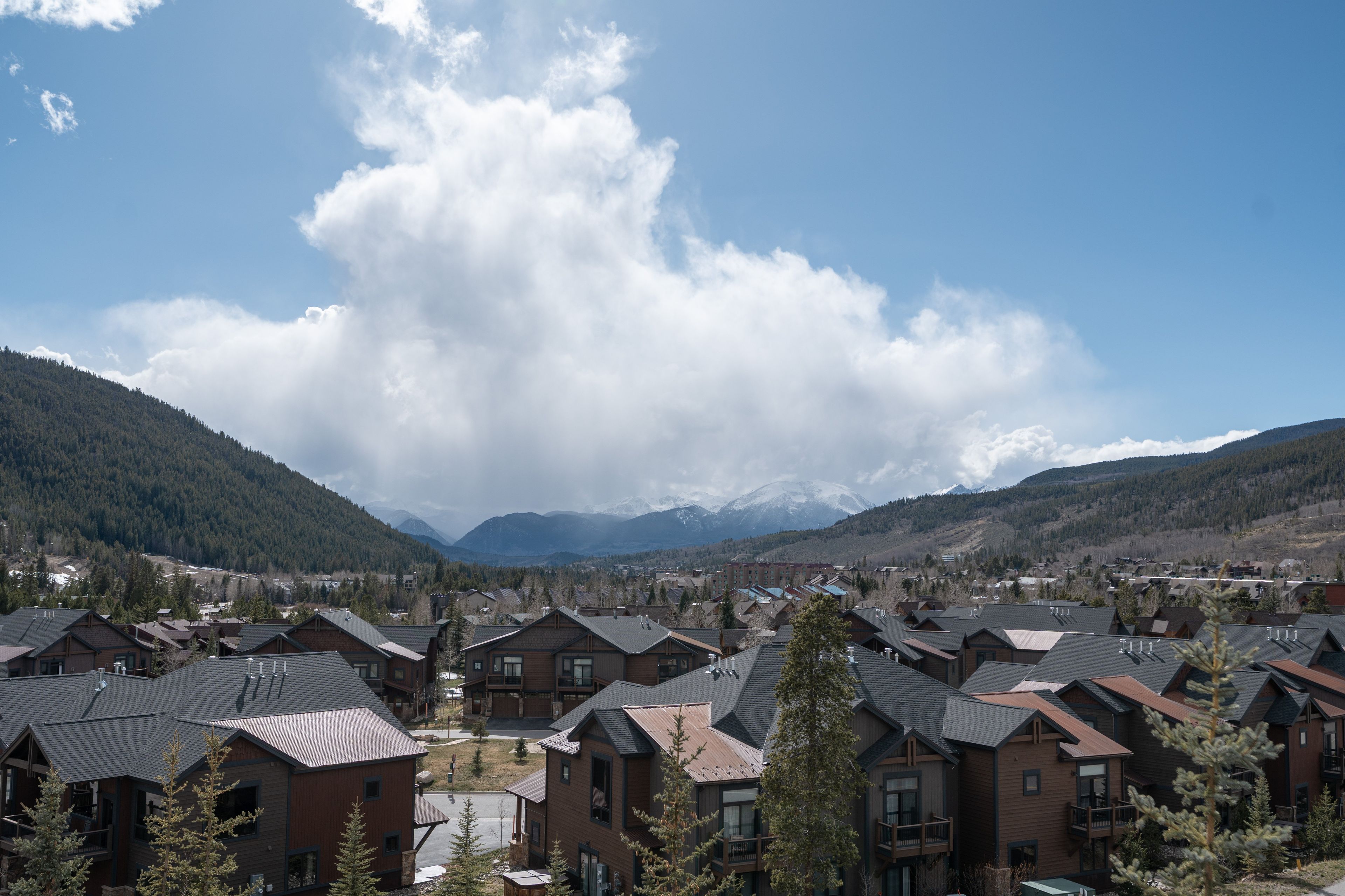 A residential area with houses featuring sloped roofs and a mountainous backdrop.
