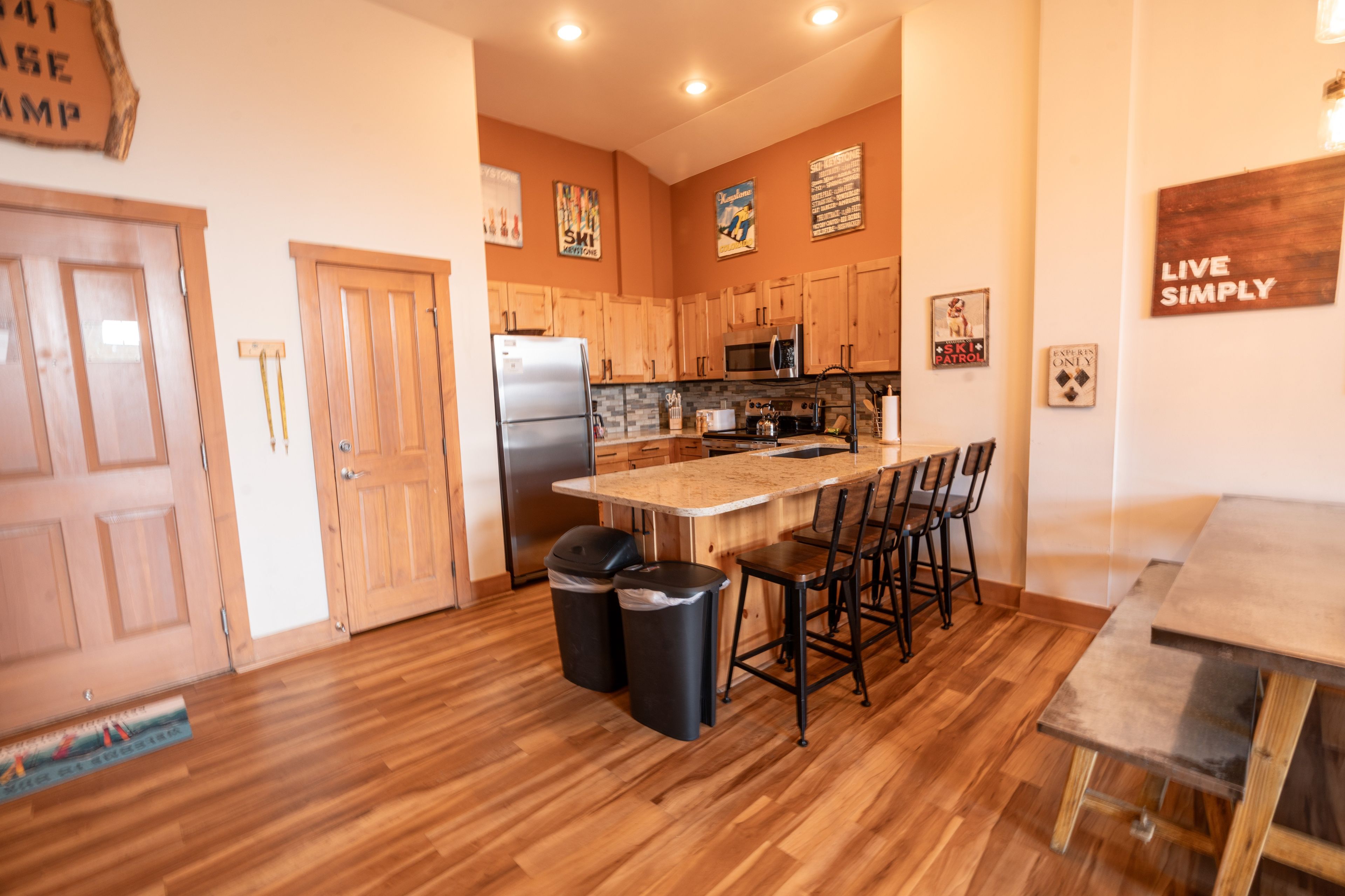 A kitchen with wooden cabinets, a stainless steel refrigerator, a microwave, and a large island with bar stools.