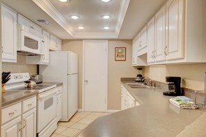 A kitchen with white cabinets, a refrigerator, a microwave, a stove, a sink, and a coffee maker. - 325 El Matador 1 Bedroom Condo (Fort Walton Beach)
