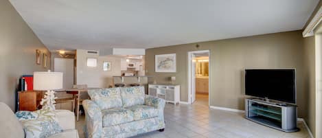 A living room with a sofa, a television, and a dining area with a table and chairs.