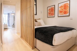 A bedroom with a bed, a wooden partition, and two framed artworks on the wall. - Studio 4 – Fully Renovated, Modern & Centrally Located (Mad)