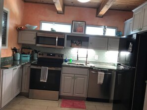 Eine Küche mit Mikrowelle, Backofen, Spüle und Kühlschrank.