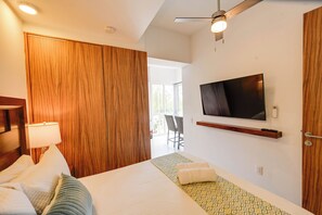 Une chambre d’hôtel avec un lit, un téléviseur fixé au mur, un ventilateur de plafond et une vue sur l’extérieur.