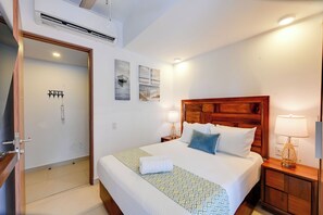 A hotel room with a bed, two bedside tables with lamps, a wooden headboard, and a door leading to a bathroom. - 2-unit Combo w/ Resort Perks < 1 Mi to Beach! (Nuevo Nayarit)