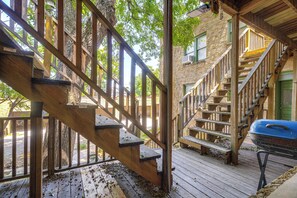 A wooden deck with a staircase leading to a green door, surrounded by trees. - San Antonio Studio Near Dining, Pearl District (San Antonio)