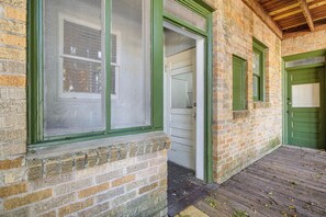 A brick building with green-framed windows and a wooden deck. - San Antonio Studio Near Dining, Pearl District (San Antonio)