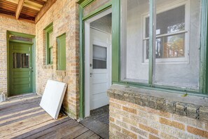 A brick building with green-framed windows and doors, a wooden deck, and a white door with a window. - San Antonio Studio Near Dining, Pearl District (San Antonio)
