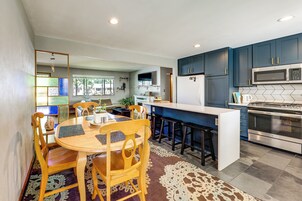 Cocina compacta con isla central, gabinetes azul oscuro y electrodomésticos de acero inoxidable.