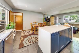 Una cocina moderna con una isla central, armarios empotrados y un comedor con sillas y una mesa.