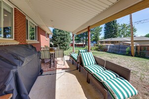 Un patio cubierto con una barbacoa, mobiliario exterior y vistas al jardín trasero.