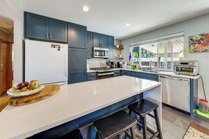 Una cocina moderna con una isla grande, electrodomésticos de acero inoxidable y armarios azules.