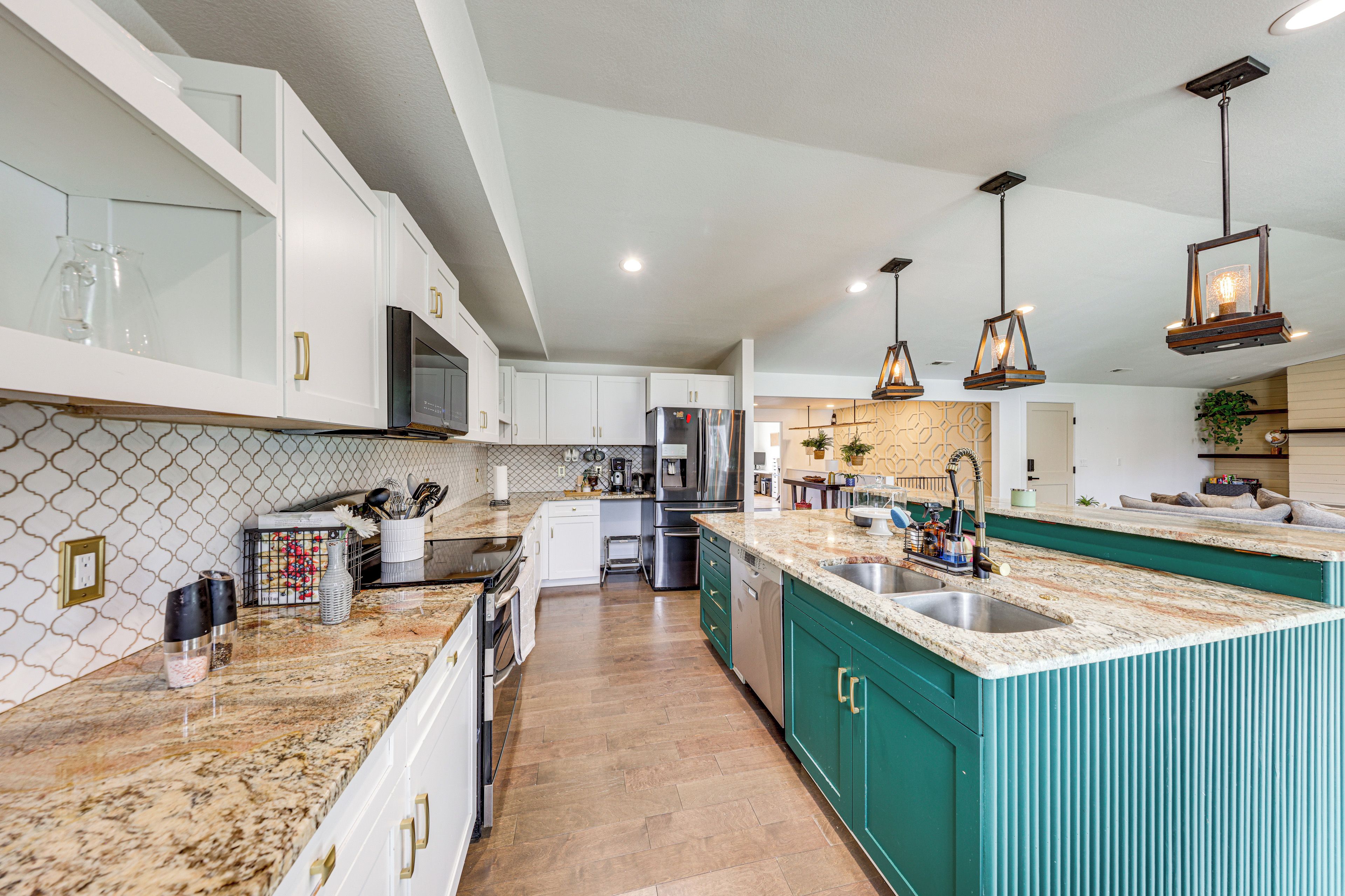 A modern kitchen with white cabinetry, a large island with a sink, and stainless steel appliances.
