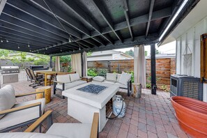 Eine Außenpatio mit Grill, Sitzgelegenheit und Feuerstelle.