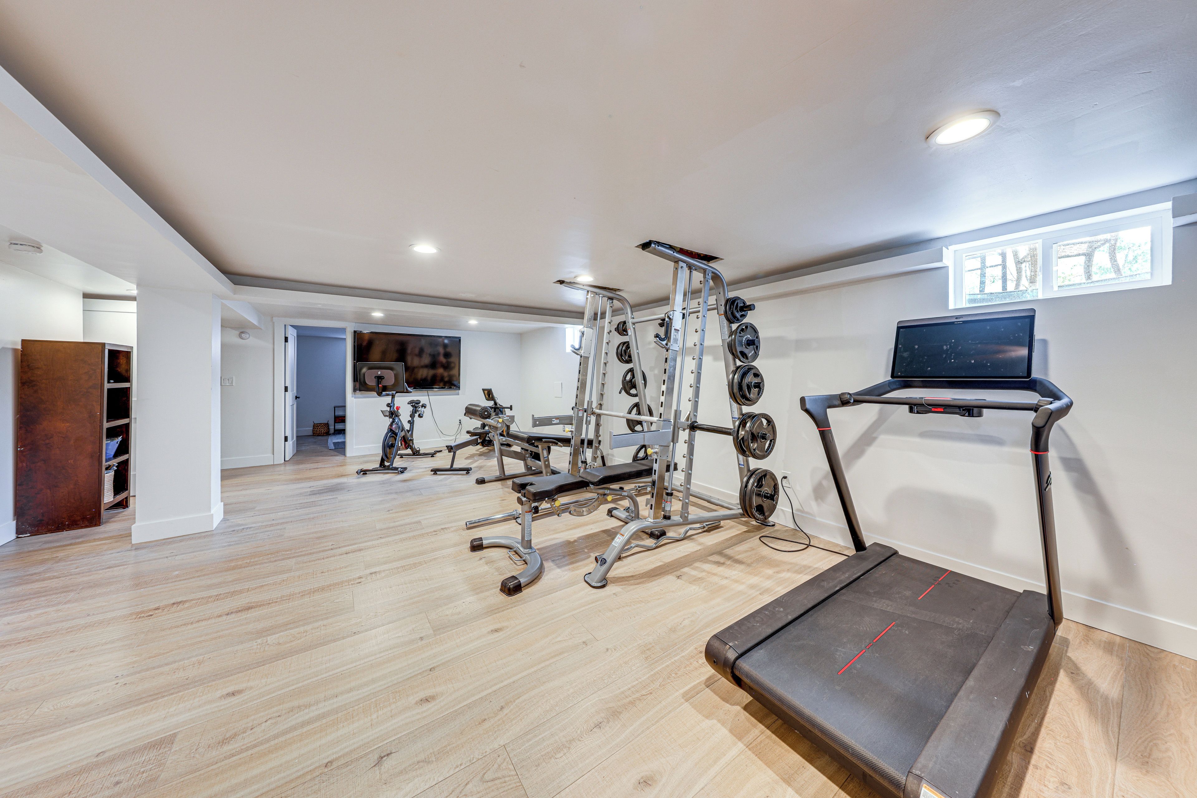 A home gym with a treadmill, weight bench, and various exercise equipment.