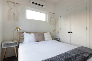 A bedroom with a bed, two bedside tables with lamps, a wardrobe, and wall-mounted decor. - East Austin Tiny Home - 4 Mi to Dtwn! (Austin)