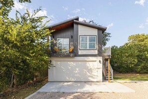 A two-story house with a garage, a balcony, and a staircase leading to an upper level. - East Austin Tiny Home - 4 Mi to Dtwn! (Austin)