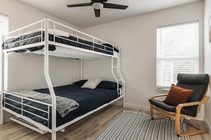A bunk bed with a desk and chair, a window with blinds, and a ceiling fan. - 4 Mi to Downtown Austin! Quiet & Quaint Home (Austin)