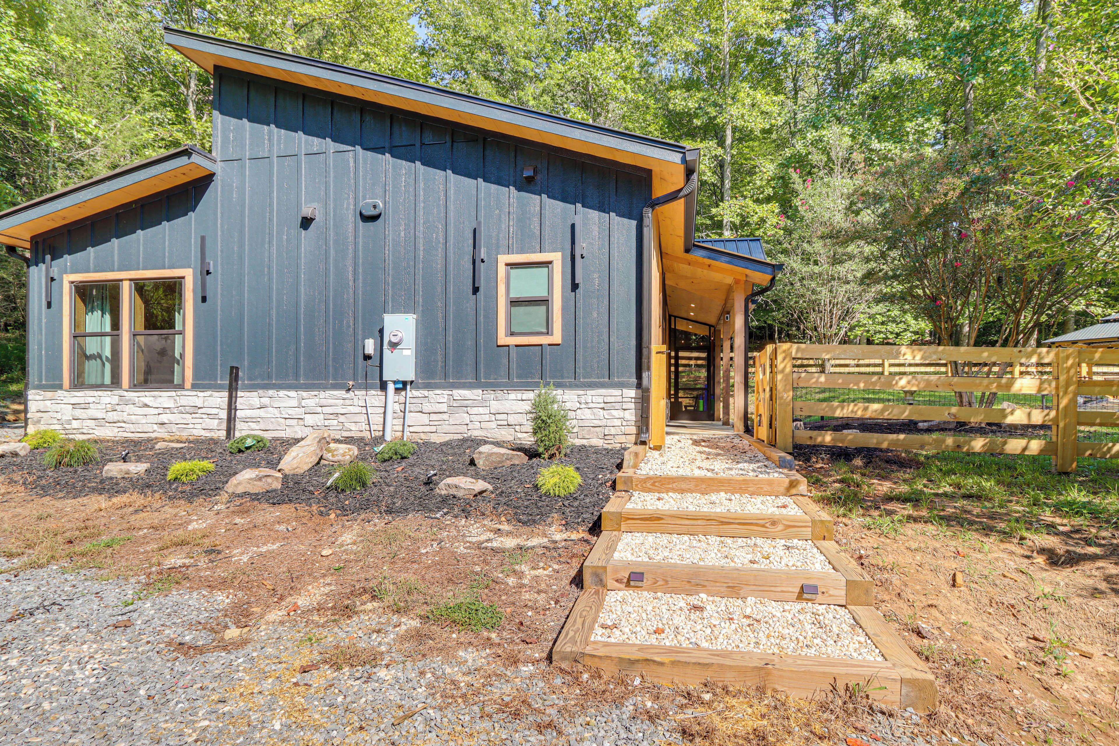 A modern house with a stone foundation, wooden deck, and a fenced yard.