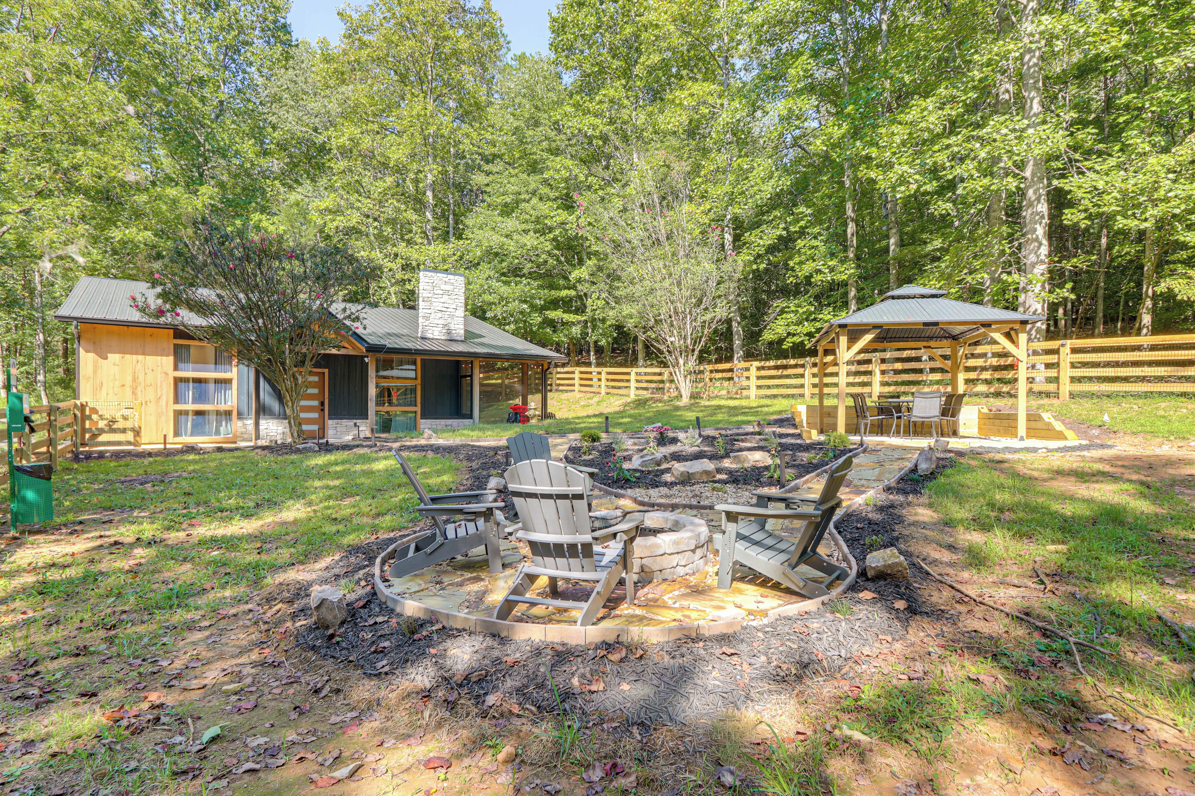 A cabin with a stone fireplace, outdoor seating, and a fenced garden area.