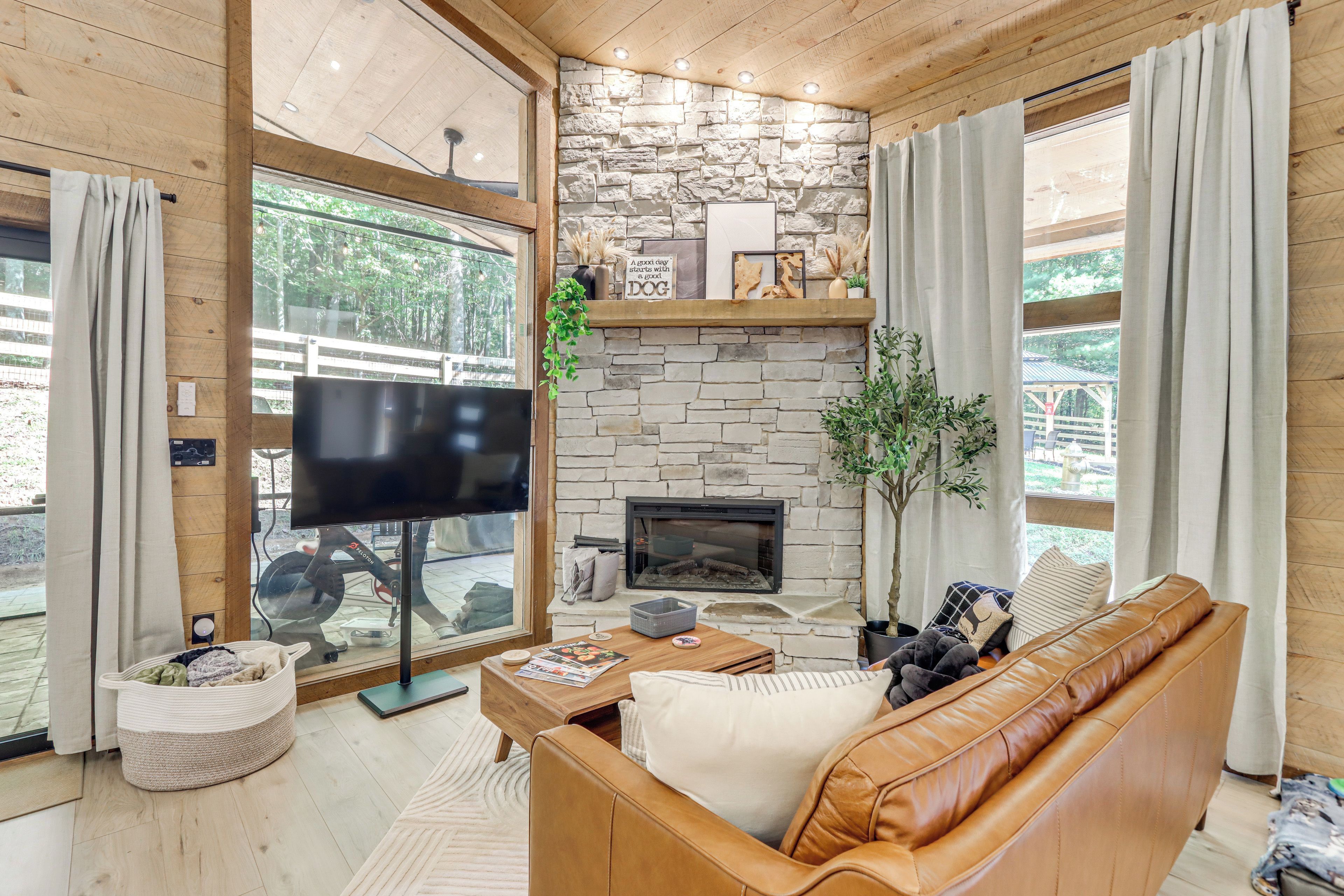 Una sala de estar acogedora con chimenea de piedra, sofá de cuero y televisor.