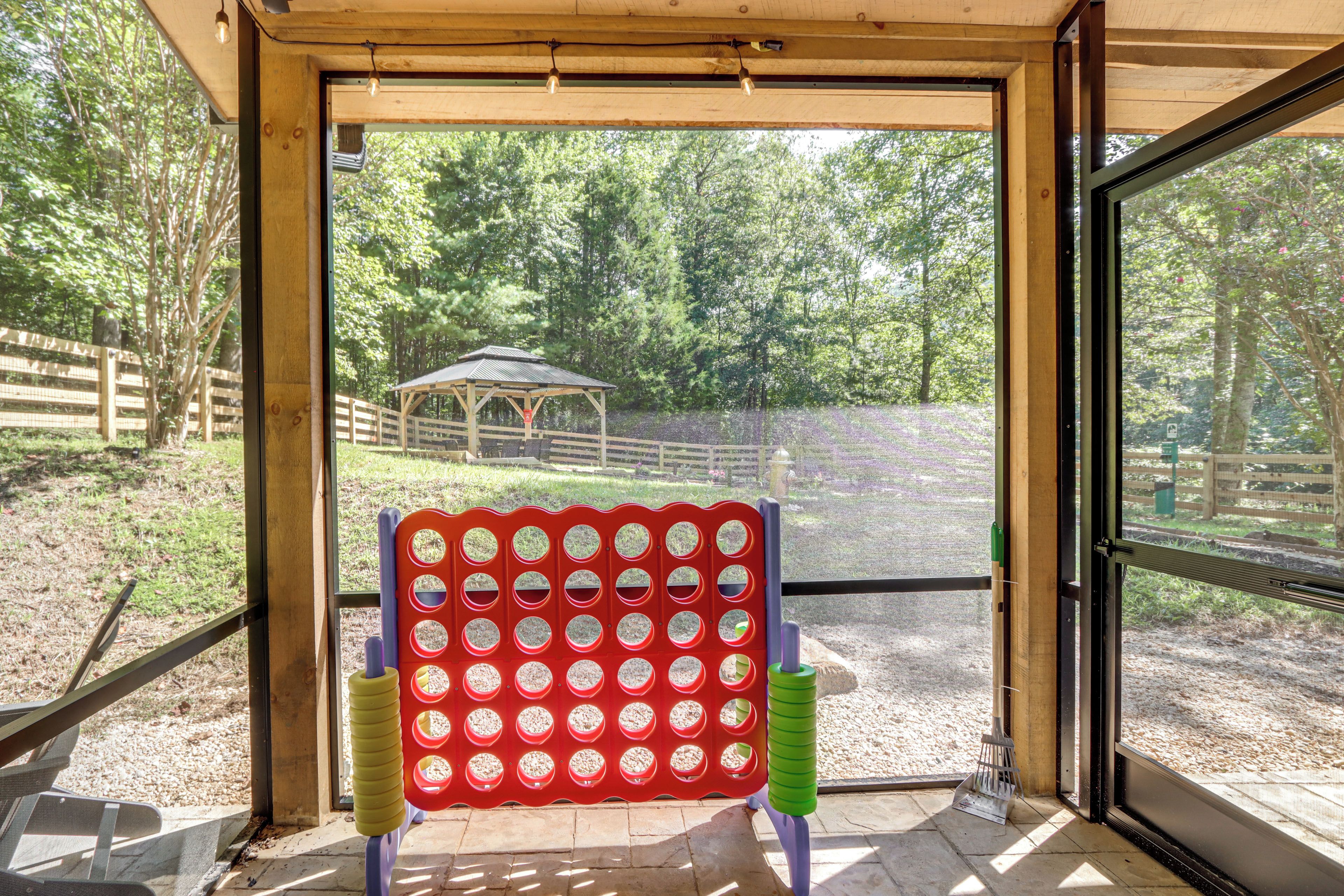 A room with a large window, a wooden ceiling, and a view of an outdoor area with a fenced enclosure and a small structure.