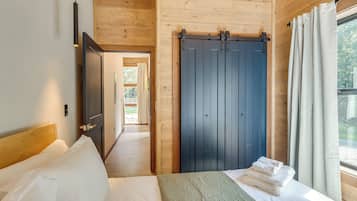 Een slaapkamer met een bed, een houten garderobe en uitzicht op het omliggende landschap.