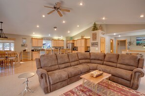 A spacious living room with a large sectional sofa, a dining area with wooden furniture, and a kitchen with wooden cabinets.