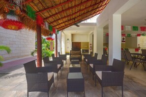 An outdoor seating area with wicker furniture, a thatched roof, and a brick wall. - 3 Mi to Beach! Condo w/ Pool in Puerto Morelos (Puerto Morelos)