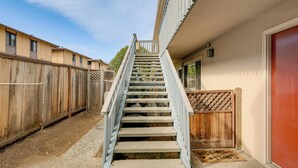 A concrete staircase leading to a building with a wooden fence on one side and a red door on the other. - 1 Mi to Beach! Walkable Extended Base in Monterey (Monterey)