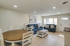 Uma sala de estar com uma mesa de jantar, dois sofás e um quadro na parede.